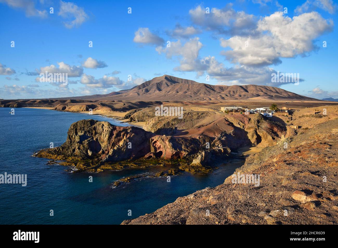 Costa de Papagayo auf Lanzarote, Spanien, mit den beiden Bars und der Bergkette Los Ajaches im Hintergrund. Ein sonniger Abend mit einigen Wolken in einem b Stockfoto