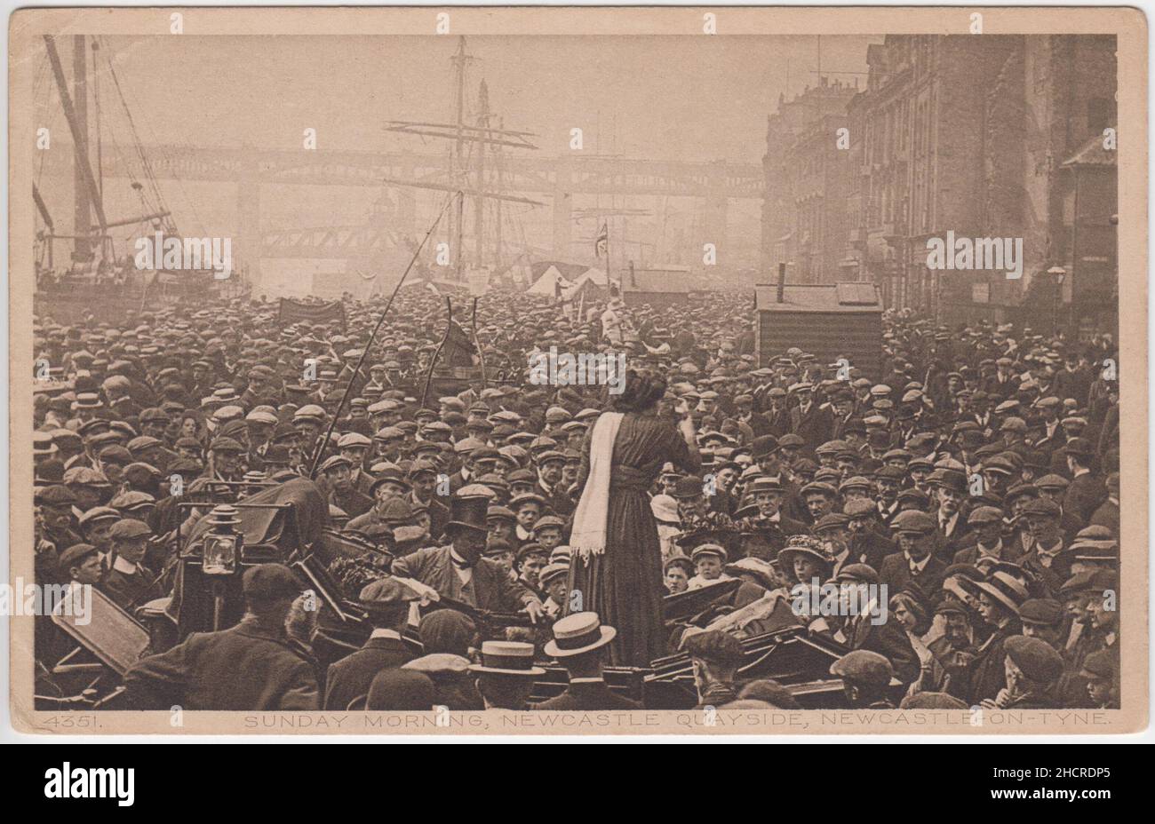 „Sonntagmorgen, Newcastle Quayside, Newcastle on Tyne“: Foto eines Massentreffens aus dem frühen 20th. Jahrhundert, das von einer in einem Wagen stehenden Frau, einem Mitarbeiter des Sprechers, einem gut gekleideten schwarzen Mann mit Zylinderhut, auf das Fahrzeug gelehnt wurde. Im Hintergrund sind Masten von Segelschiffen zu sehen. Das Thema des Treffens ist unklar, es gibt keine Banner mit Slogans und das Publikum ist größtenteils männlich (und trägt flache Kappen). Stockfoto