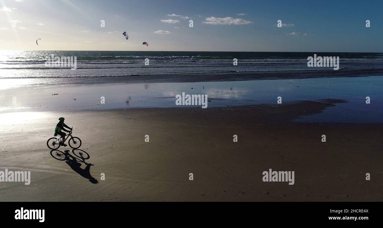 Luftaufnahme eines Silhouetten-Mannes, der auf einem Fahrrad mit fetten Reifen am Pacific Beach mit Schatten fährt, bei Sonnenuntergang, San Diego, Kalifornien, USA Stockfoto