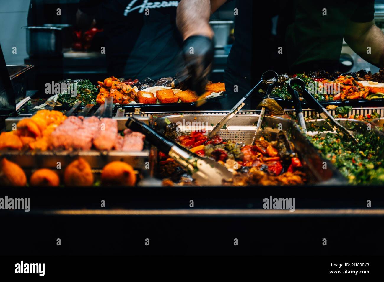 Gerichte werden in einer Cafeteria mit Köchen im Hintergrund angezeigt Stockfoto