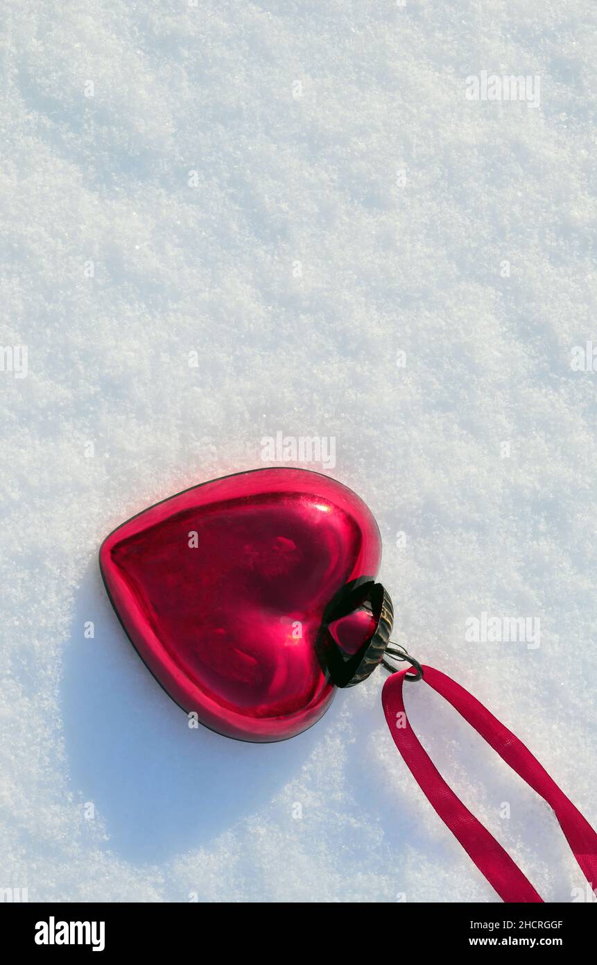 Rotes Herz auf schneebedecktem Hintergrund im Winter. Feiertage. Happy Valentinstag Feier. Konzept der Herzliebe. Stockfoto