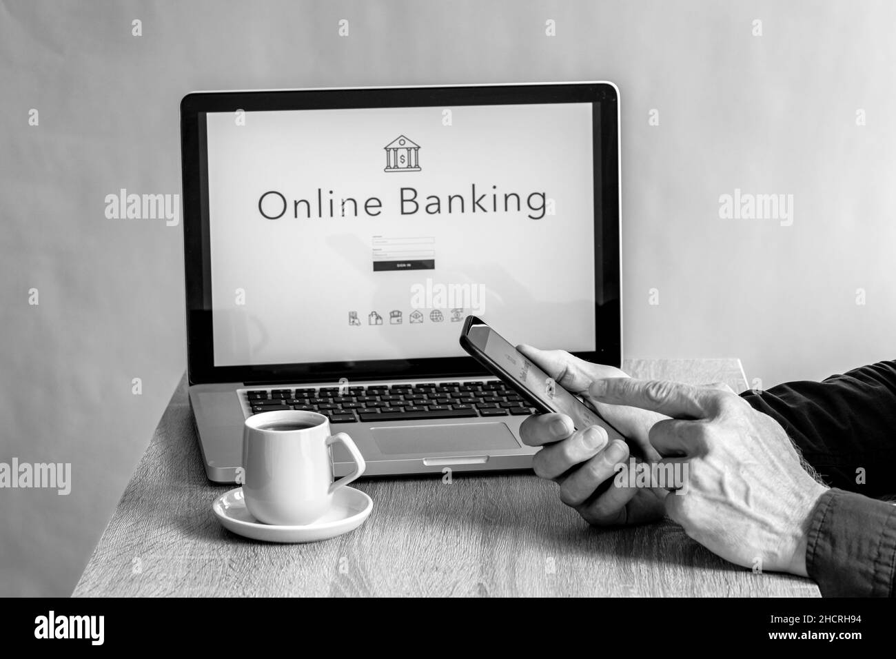Nahaufnahme von männlichen Händen, die neben einem Laptop auf das Telefon tippen, Online-Banking-Konzept Stockfoto