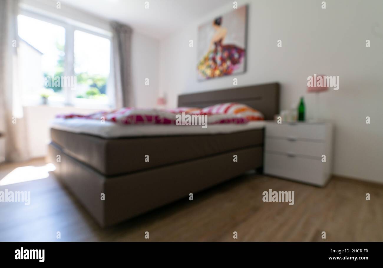 Verschwommenes Schlafzimmer mit weißem und farbenfrohem Bett Stockfoto