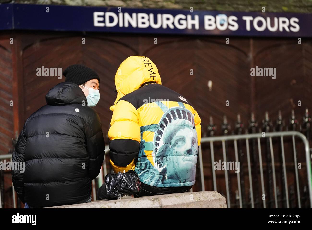 Ein Paar sitzt auf der Waverley Bridge im Zentrum von Edinburgh vor den Glocken am Silvesterabend. Bilddatum: Freitag, 31. Dezember 2021. Stockfoto