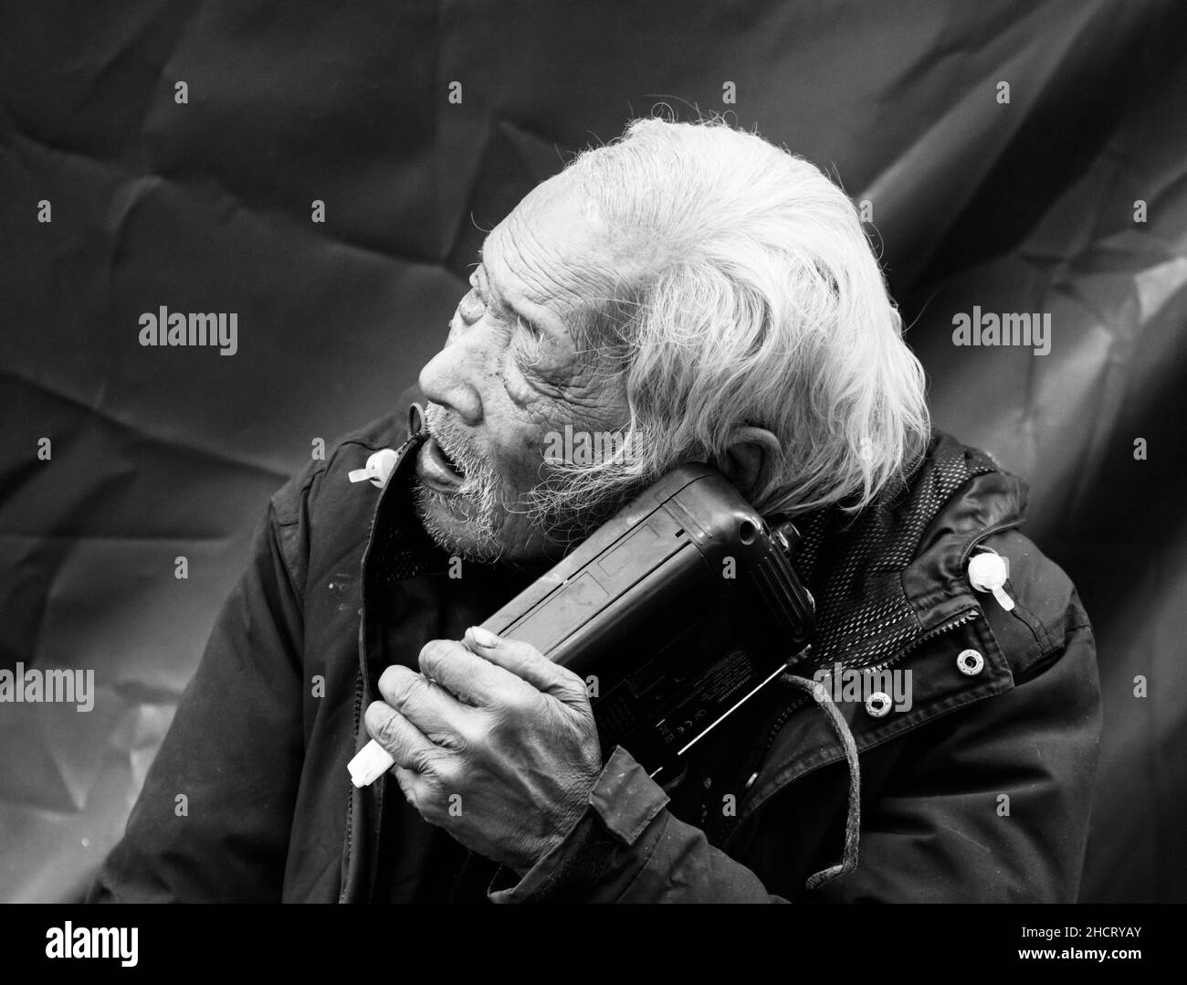 Ein älterer Bürger hört das Radio in Central, Hongkong Stockfoto