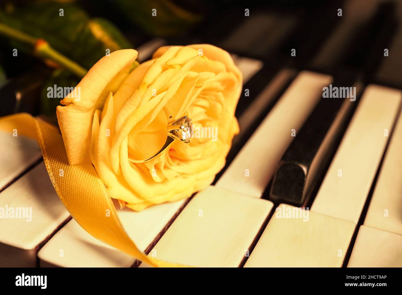 Verlobungsring mit Rose und Band auf Klaviertasten, Nahaufnahme Stockfoto