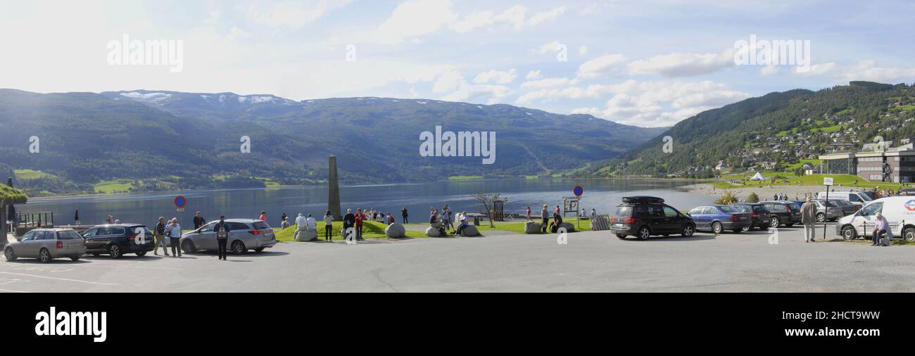 Panorama von Voss Hordaland Norwegen Europa Steinmonument vor dem See Vangsvatnet mit Fahrzeugen auf beiden Seiten geparkt Stockfoto