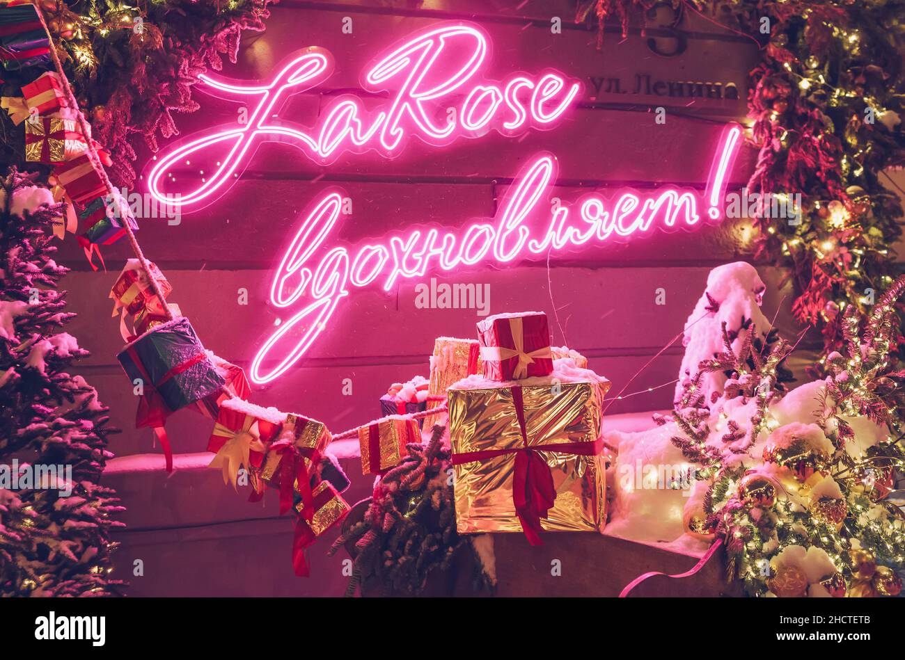 Nowosibirsk, Russland, 18. dezember 2021: Leuchtendes Neonschild in russischer Sprache mit der Bedeutung „La Rose (floral Shop Chain) inspires“ mit Weihnachtsdekorationen im Winter Stockfoto