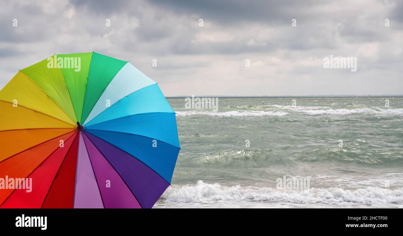 Bunt von Regenschirm am Strand und Schaum von Meereswellen bei einem Gewitter, Wetter Konzept Bild Stockfoto