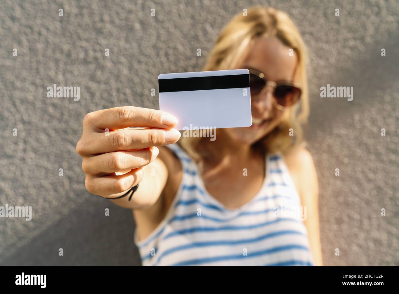 Porträt einer hübschen jungen Frau in Pullover mit Kreditkarte im Gesicht gekleidet. Copyspace für Ihren individuellen Text. Stockfoto