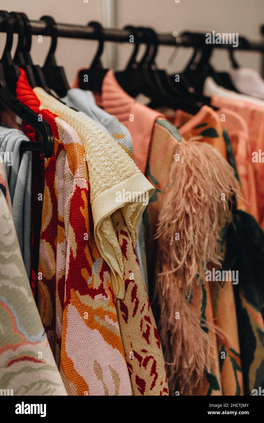 Designer-Mode-Outfits hängen in einer Reihe auf der Backstage der Fashion Week. Vertikal Stockfoto