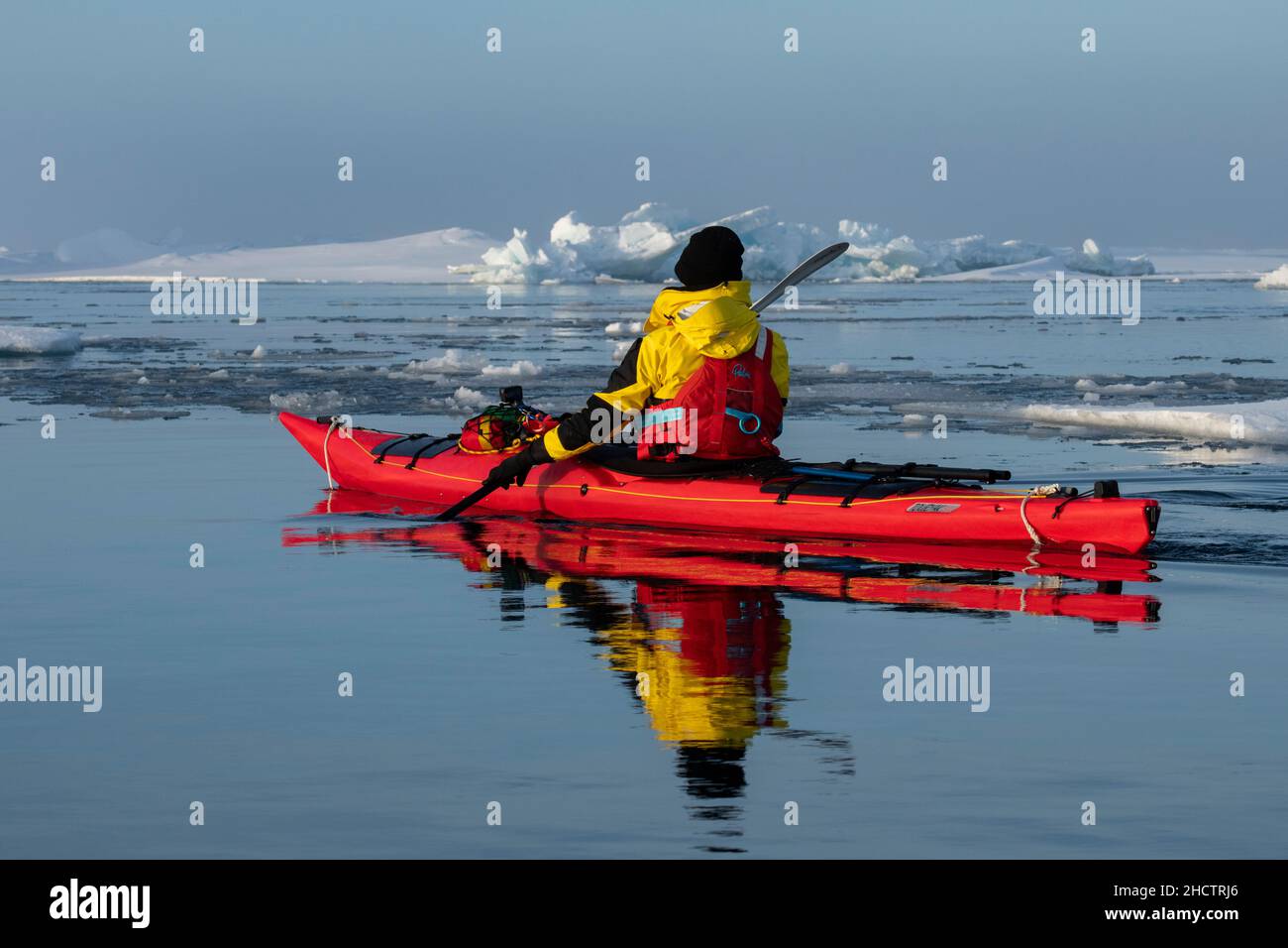 Norwegen, Spitzbergen. Kajakfahren im Meer zwischen Eisbergen in ruhiger See. Stockfoto