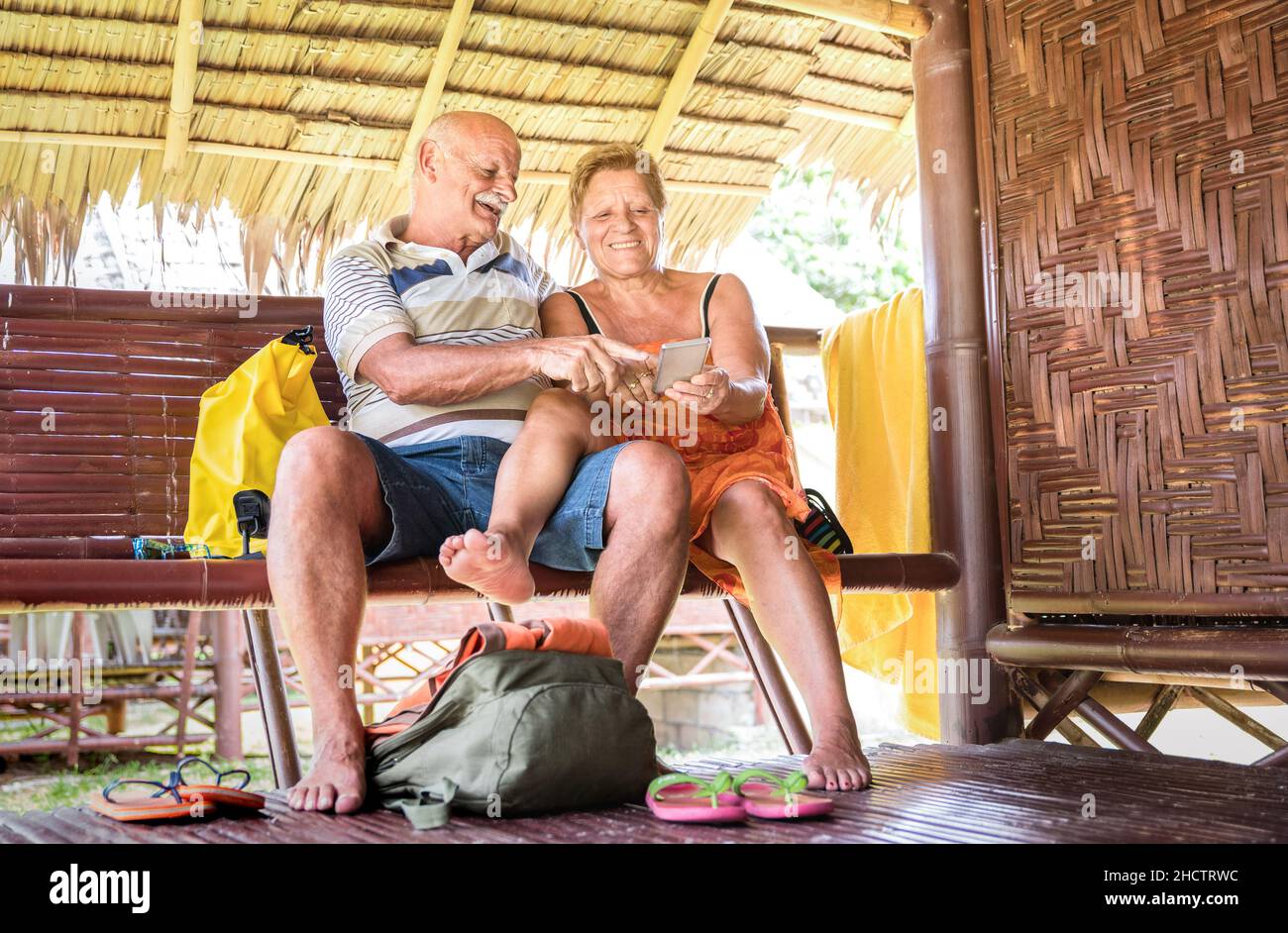 Glückliches Seniorenpaar mit Handy im Luxus-Bungalow-Resort - Aktive Senioren und Reisekonzept immer mit neuen Trends verbunden Stockfoto Glückliches Seniorenpaar mit Handy im Luxus-Bungalow-Resort - Aktive Senioren und Reisekonzept immer mit neuen Trends verbunden Stockfoto