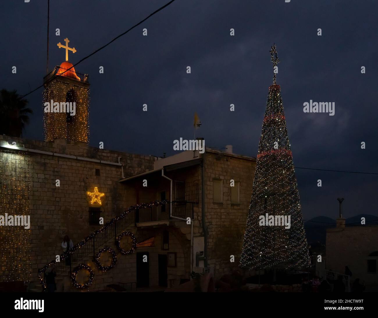 Mi'ilia, Israel - 25th. Dezember 2021: Die Kirche und ein weihnachtsbaum, geschmückt zu weihnachten in dem arabisch-christlichen Dorf Mi'ilia, Israel, am twil Stockfoto