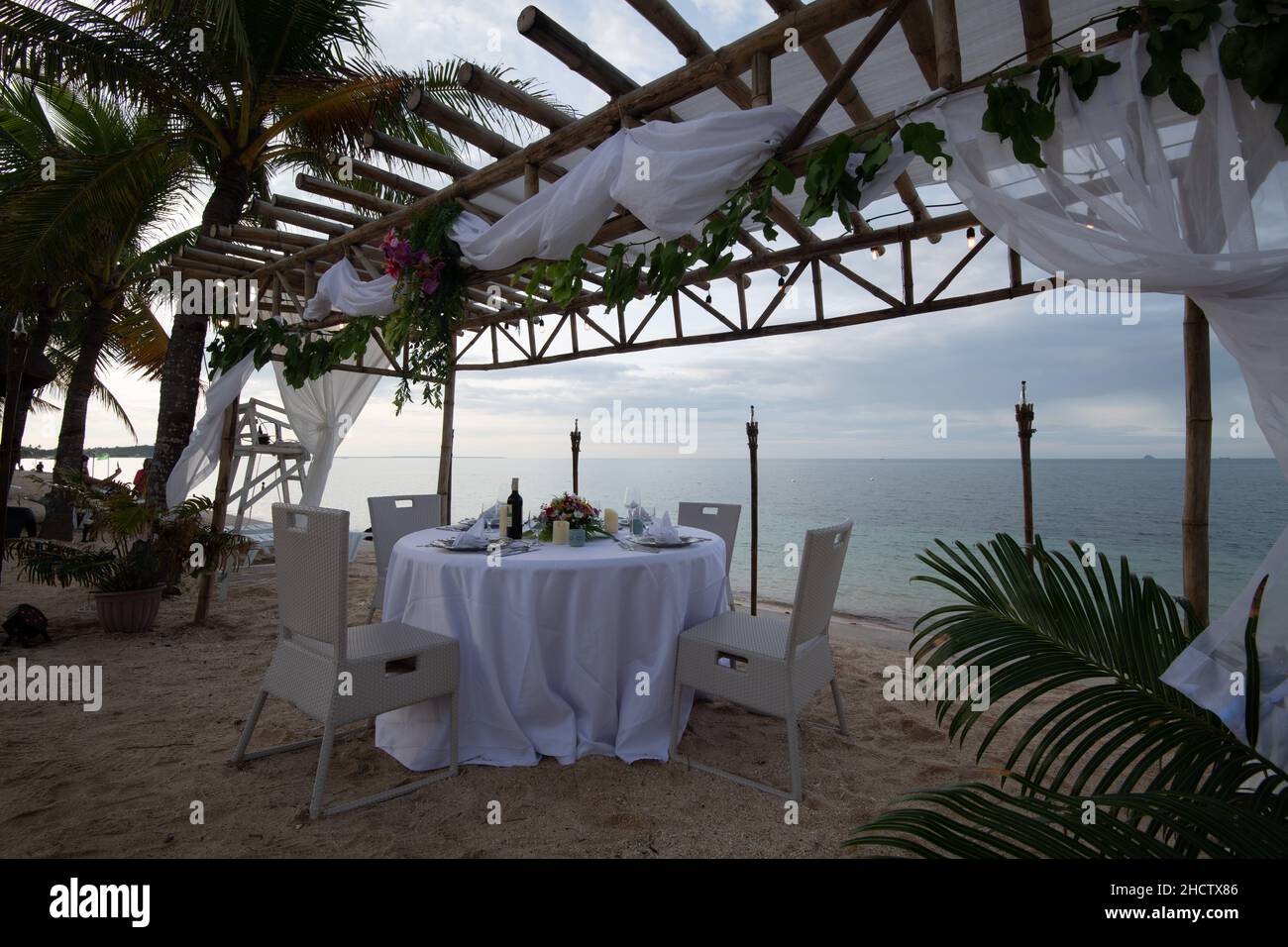 Ein Blick auf das Meer und ein hölzernes Baldachin mit einem wunderschön dekorierten Esstisch Stockfoto