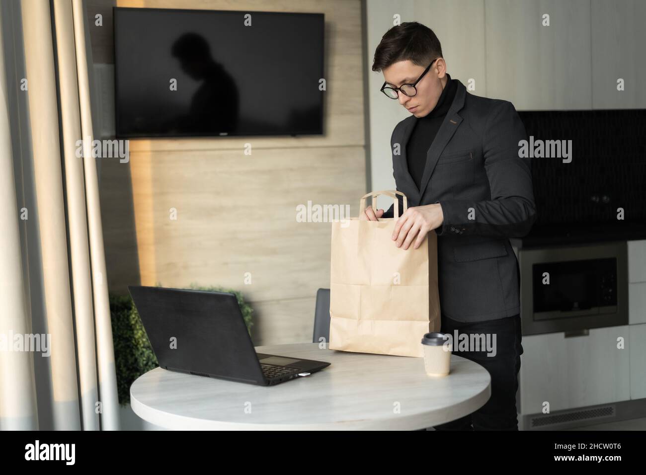 Lebensmittelzustellung Home Office, Mann Auspacken Lunchpaket in Einweg-Gericht, Geschäftsmann Freiberufler Essen zum Mitnehmen, zu Hause essen Stockfoto