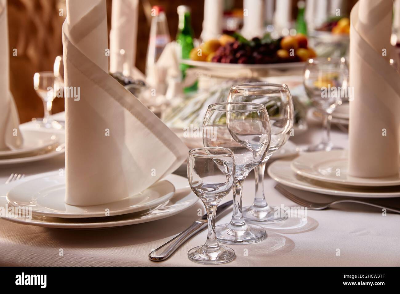 Tischeinstellung im Restaurant. Teller, Gläser, Gabeln und Messer, Servietten auf der Tischdecke auf dem Tisch Stockfoto