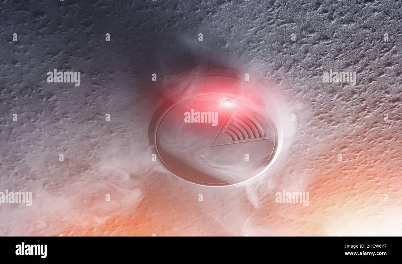Rauchmelder mit weißem Rauch und roter Warnleuchte Stockfoto
