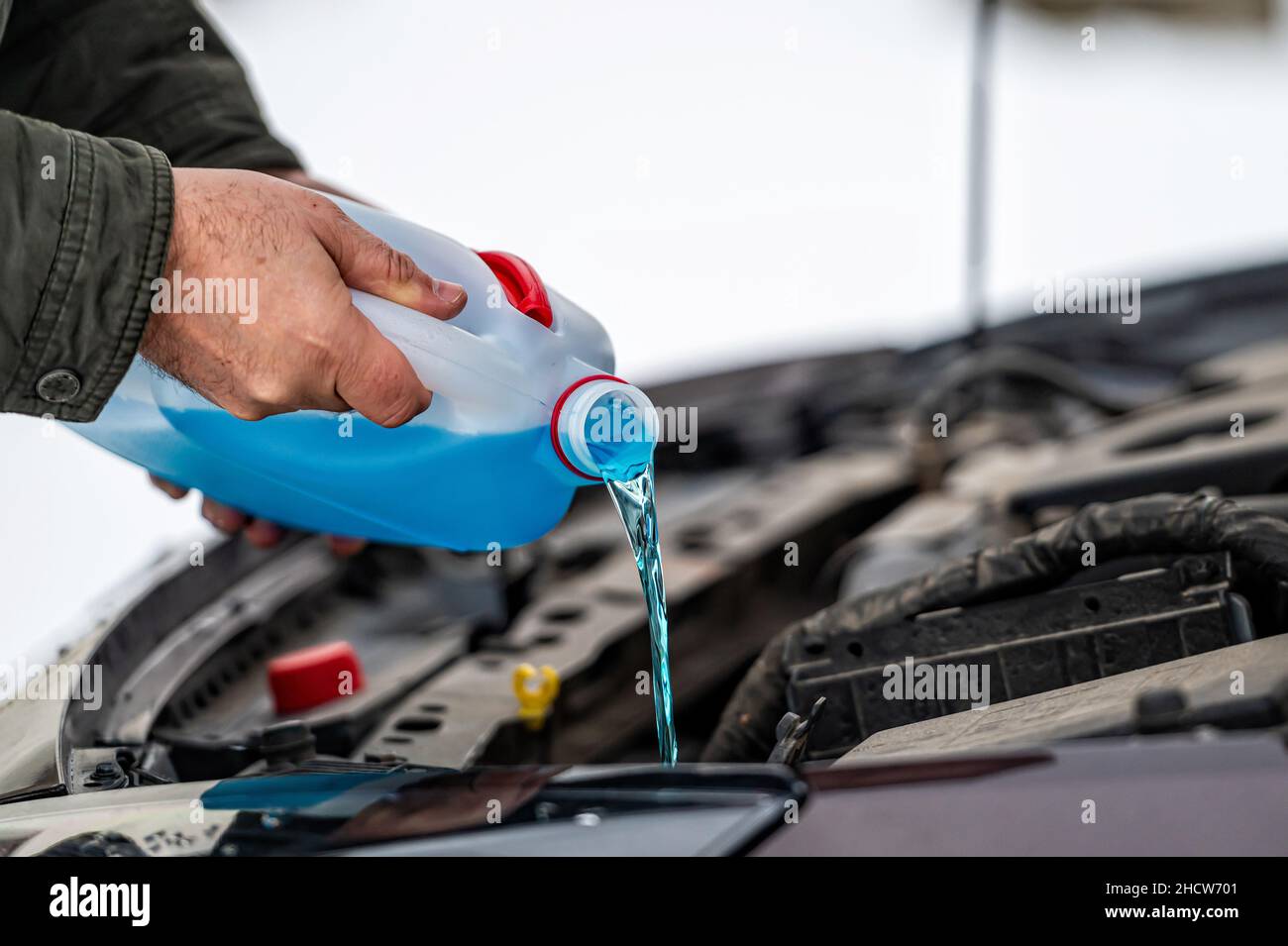 Fahrer befüllen die blaue, nicht gefrierende Scheibenwaschflüssigkeit in den Tank des Fahrzeugs, Nahaufnahme Stockfoto