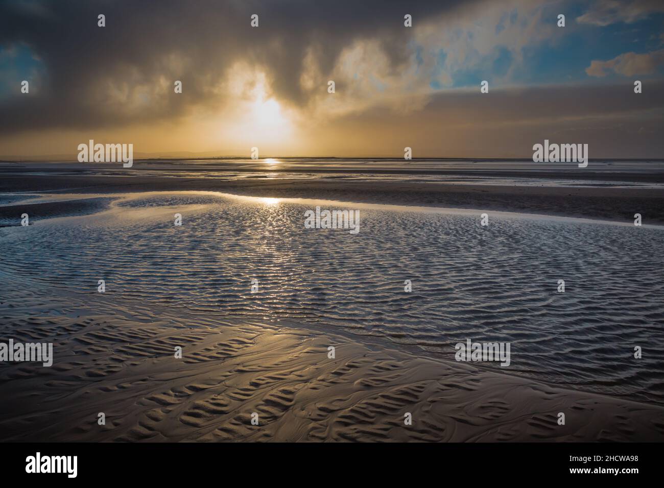 Strand bei Sonnenuntergang im Winter bei Ebbe mit launischer Atmosphäre Stockfoto