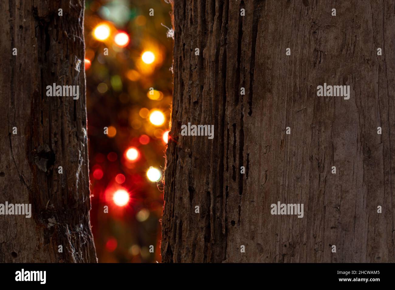 Die Feiertagslichter sind durch einen Riss im alten Zaun sichtbar. Selektiver Fokus. Stockfoto