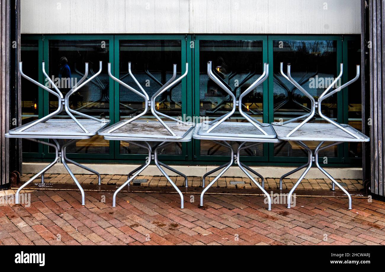 Für den Winter gestapelte Tische im Freien vor einem Restaurant Stockfoto