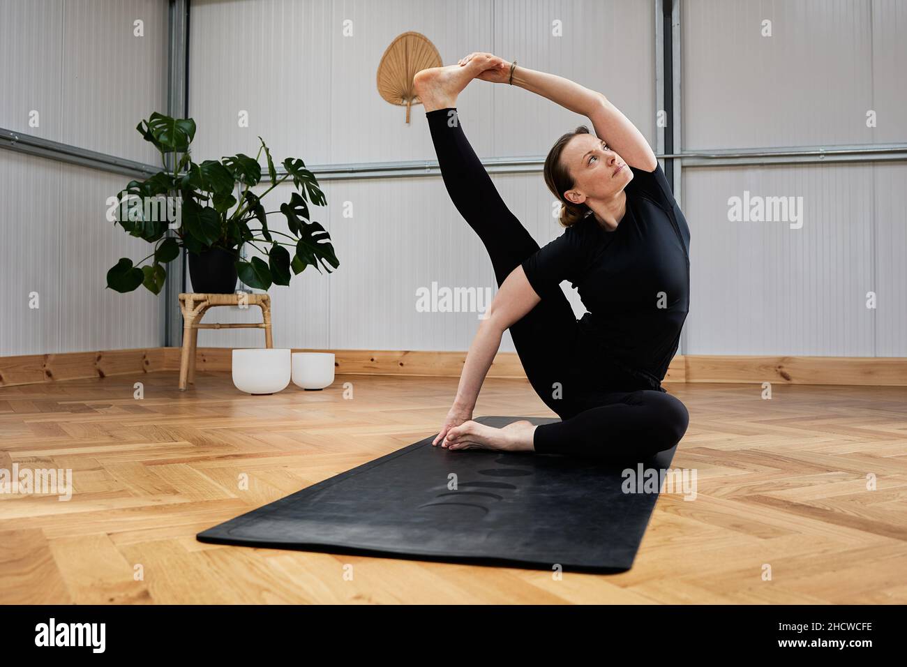 Frau, die Yoga-Haltungen auf fortgeschrittenem Niveau durchführt. Sportanweisungen Stockfoto