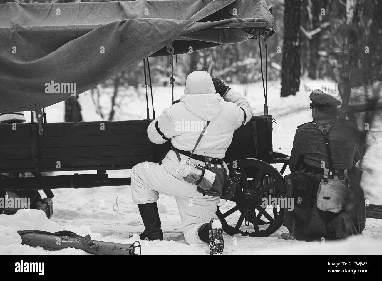 Wehrmachts-Infanterie-Soldat im Zweiten Weltkrieg Soldaten sitzen in Hinterhalt in der Nähe des Bauernwagens im Winterwald und betrachten Ferngläser der Alten Armee Stockfoto
