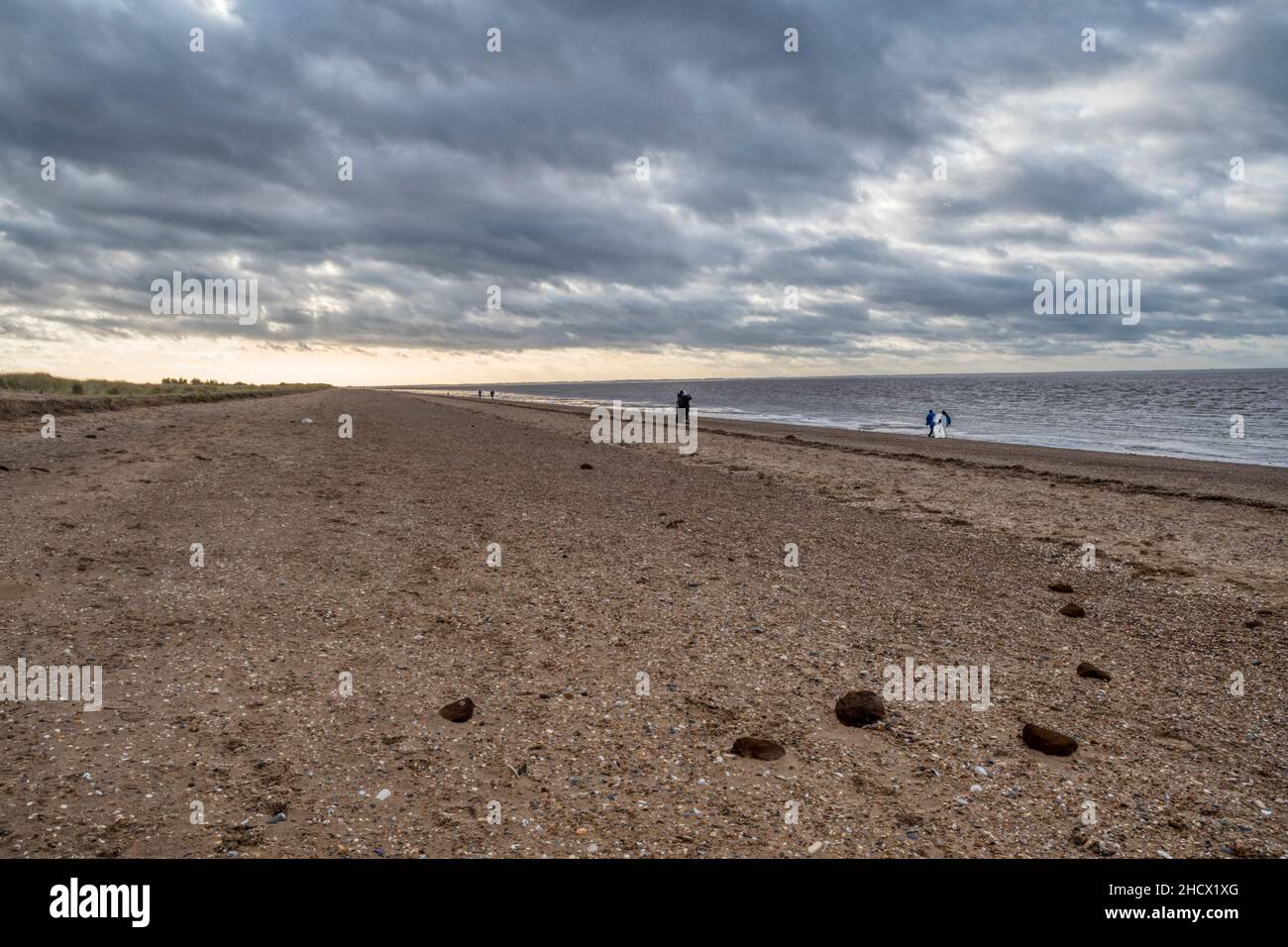 Menschen, die am Silvesterabend, 2021. Dezember, am Snettisham-Strand in Norfolk spazieren gehen. Stockfoto