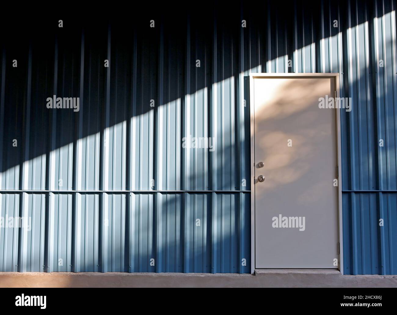 Metallgebäude im Hintergrund. Stahlbauwand mit Tür- und Lichtmuster Stockfoto