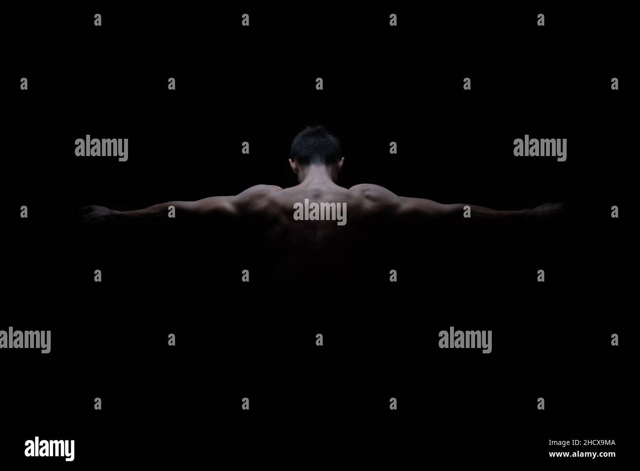 Junger männlicher Athlet posiert vom Rücken mit Armen an den Seiten und zeigt Muskeln und Kraft für Werbung oder Präsentation. Speicherplatz kopieren Stockfoto