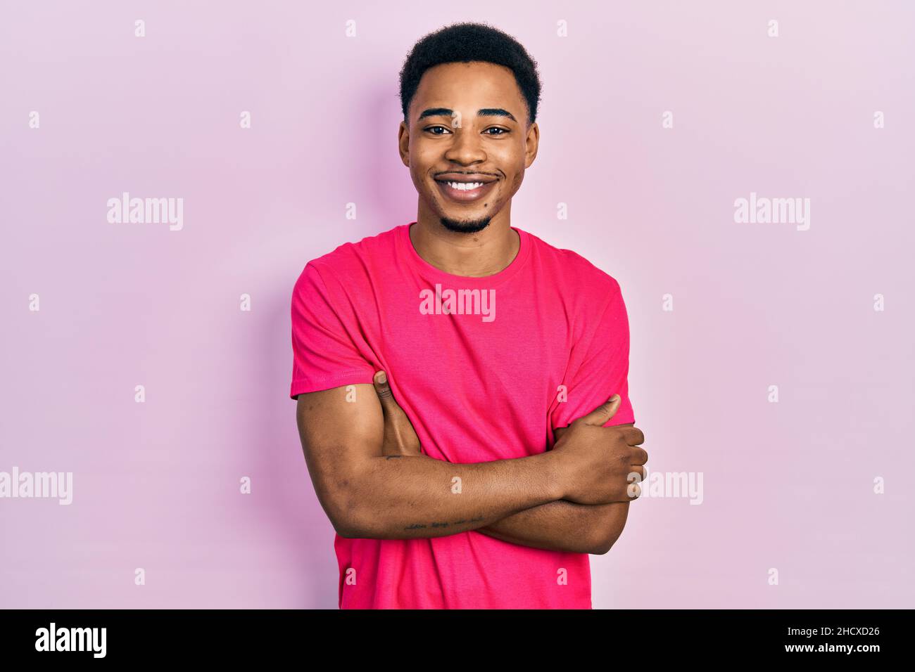 Junger afroamerikanischer Mann trägt Casua T-Shirt glückliches Gesicht lächelnd mit gekreuzten Armen Blick auf die Kamera. Positive Person. Stockfoto