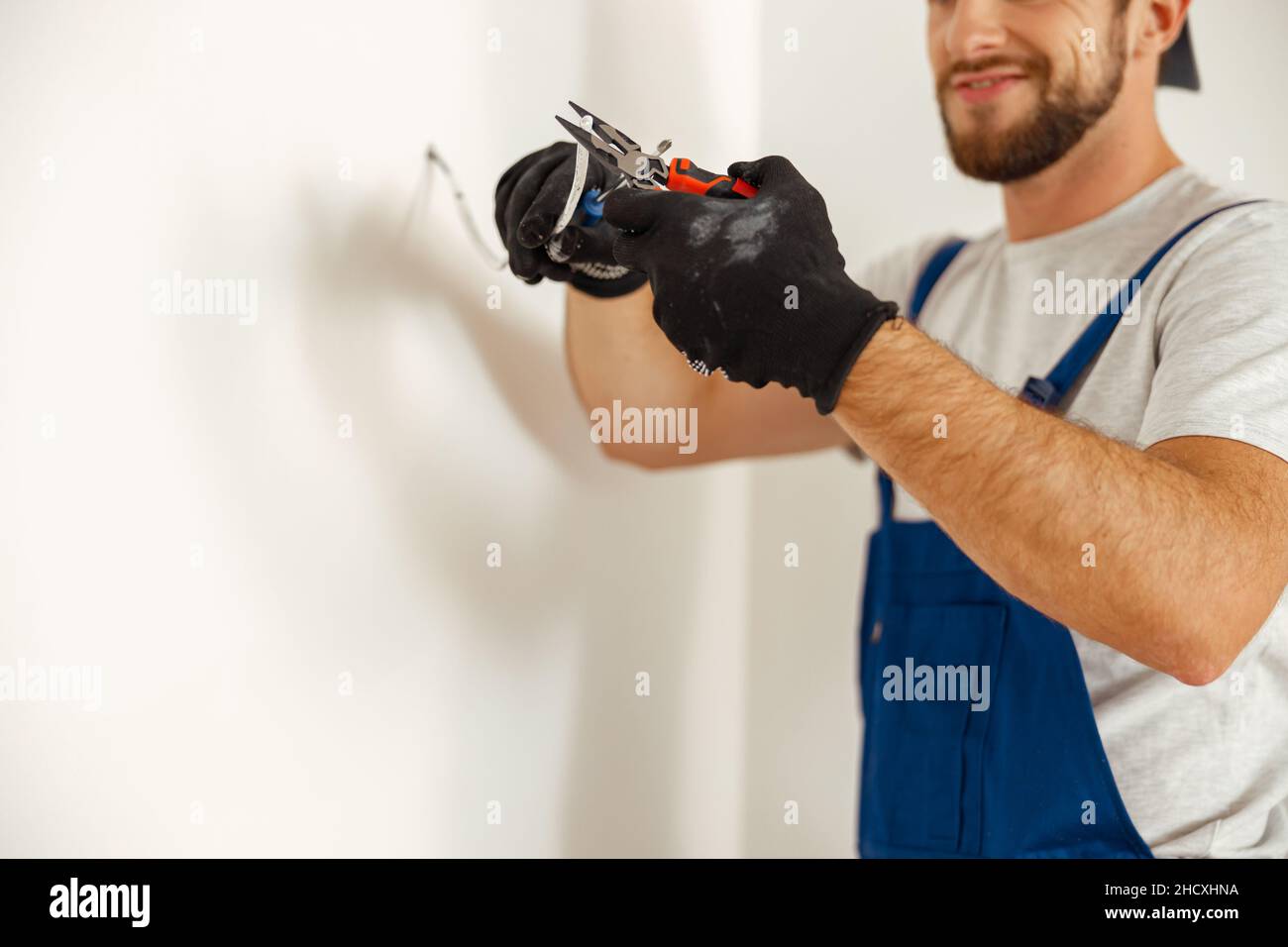 Hände von Elektriker mit Zangen beim Schneiden von Drähten, Arbeiten an Wohn-elektrische System in neuem Haus Stockfoto