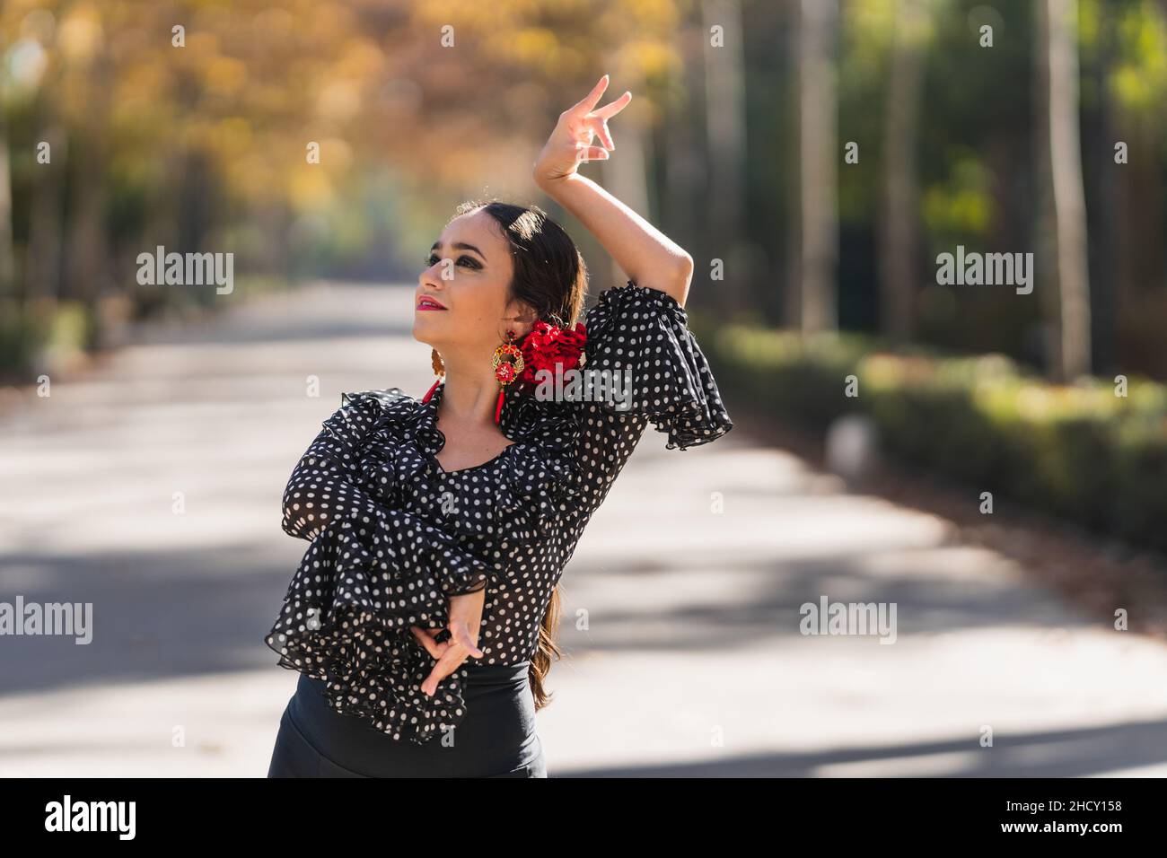 Frau in einem Flamenco-Kleid und Nelken auf ihrem Kopf tanzen im Freien Stockfoto
