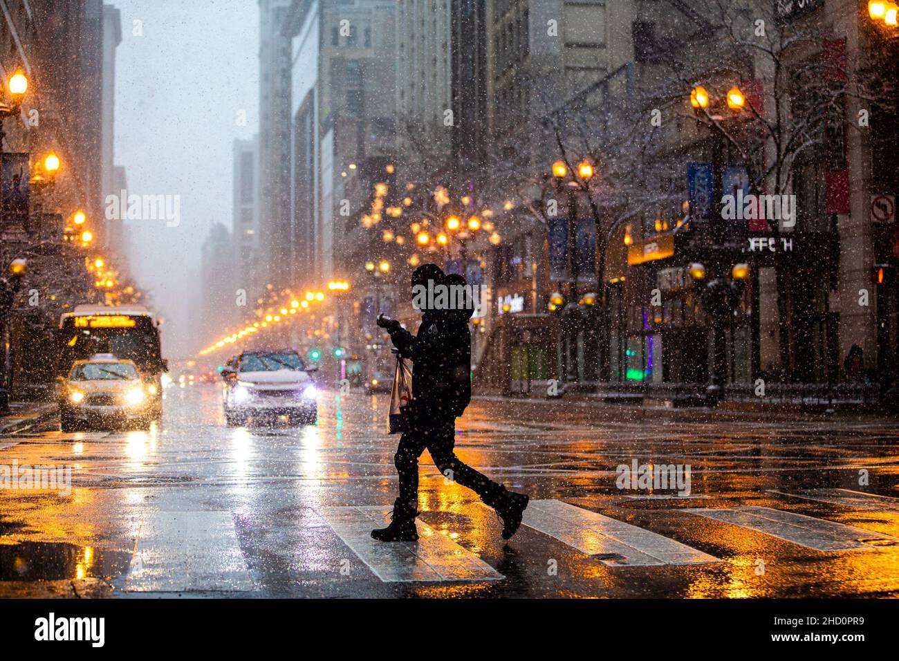 Chicago, USA. 1st Januar 2022. Am 1. Januar 2022 überquert ein Mann die State Street in der Innenstadt von Chicago, den Vereinigten Staaten. Ein Wintersturm traf Chicago am Samstag, mit Schneeansammlungen, die voraussichtlich 10 bis 18 Zentimeter erreichen werden. Kredit: Vincent D. Johnson/Xinhua/Alamy Live Nachrichten Stockfoto