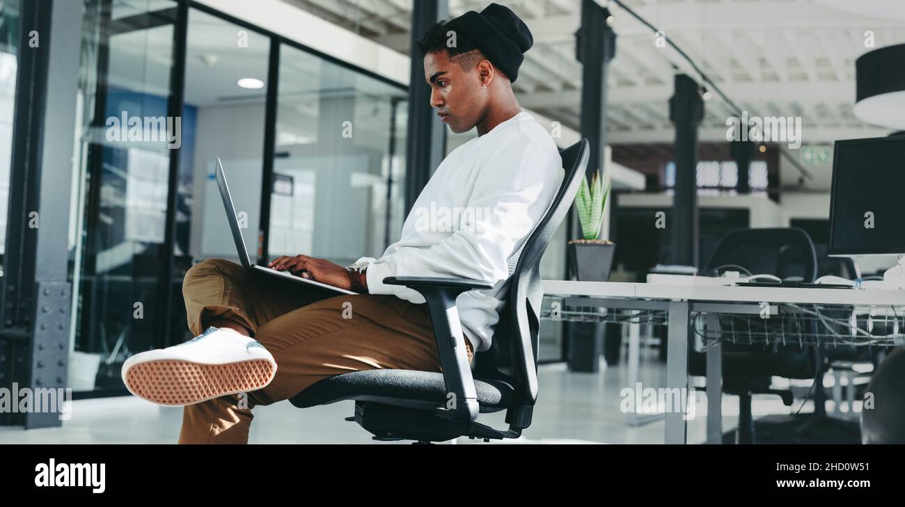 Geschäftsmann, der an einem neuen Softwareprogramm arbeitet. Fokussierter junger Softwareentwickler, der während der Arbeit im Büro einen Laptop verwendet. Kreativer Geschäftsmann Stockfoto