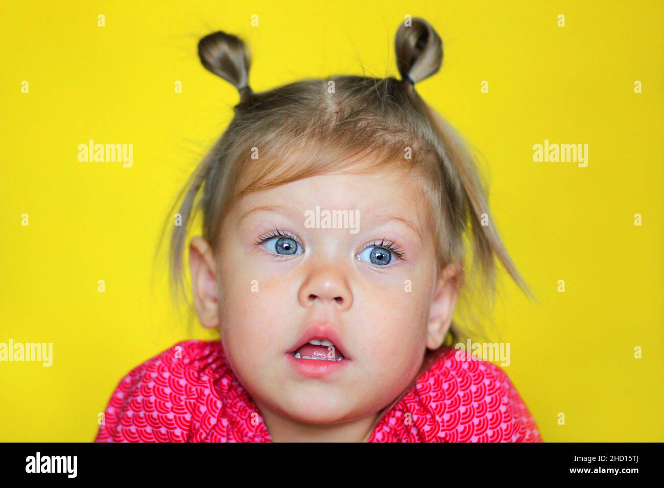 Porträt von verwirrt kaukasischen Kind Kind Mädchen von 2 Jahren mit offenem Mund auf gelbem Hintergrund Stockfoto