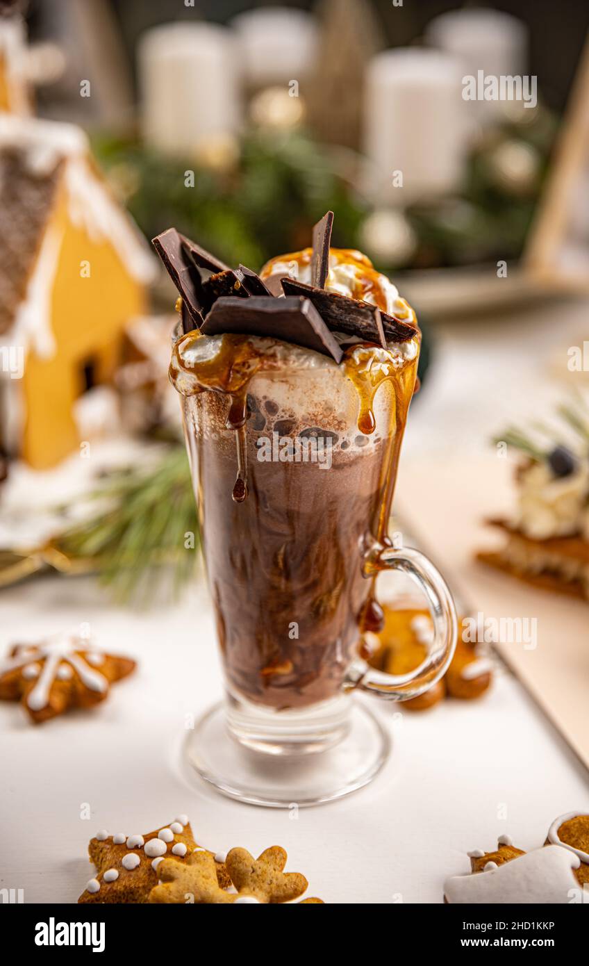 Heiße Schokolade mit Schlagsahne, Schokoriegel und Karamellsauce in hohem Glas Stockfoto