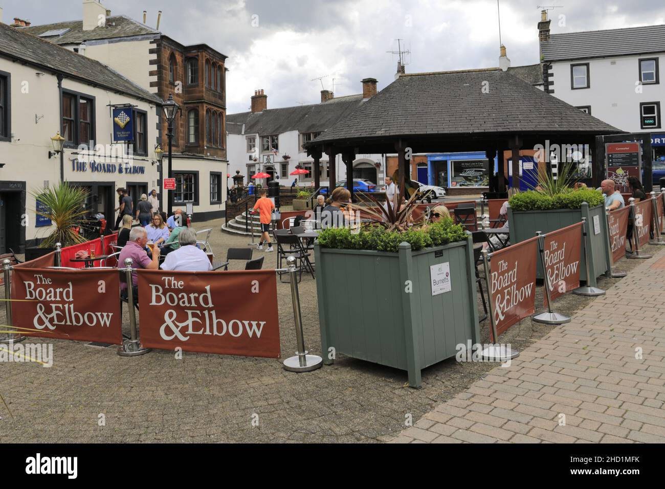 Personen außerhalb des Verwaltungsrats und des Elbow Pub, Penrith Town, Cumbria, England, Großbritannien Stockfoto