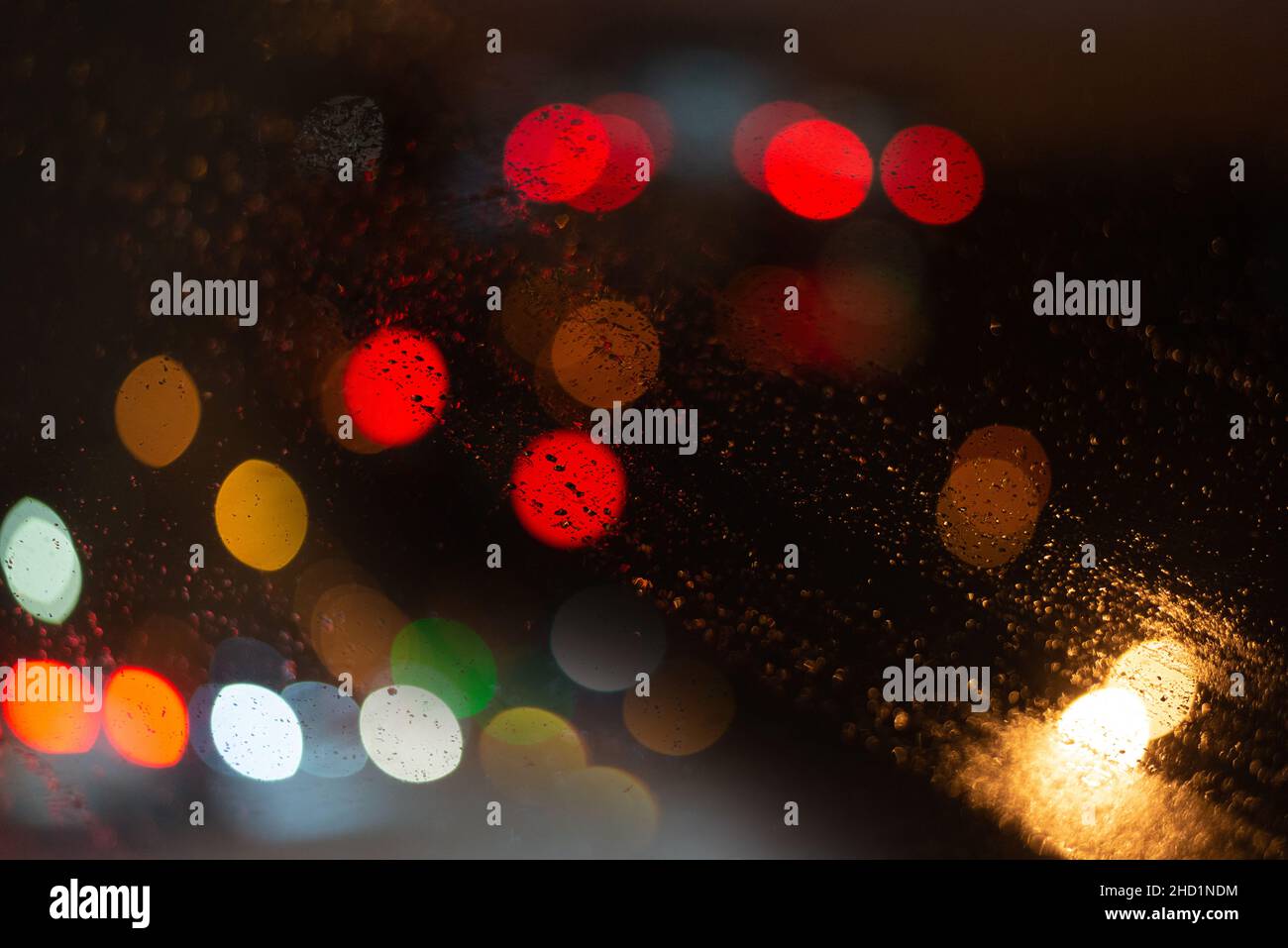 Unscharfer Hintergrund mit Regentropfen und Lichtern. Stockfoto