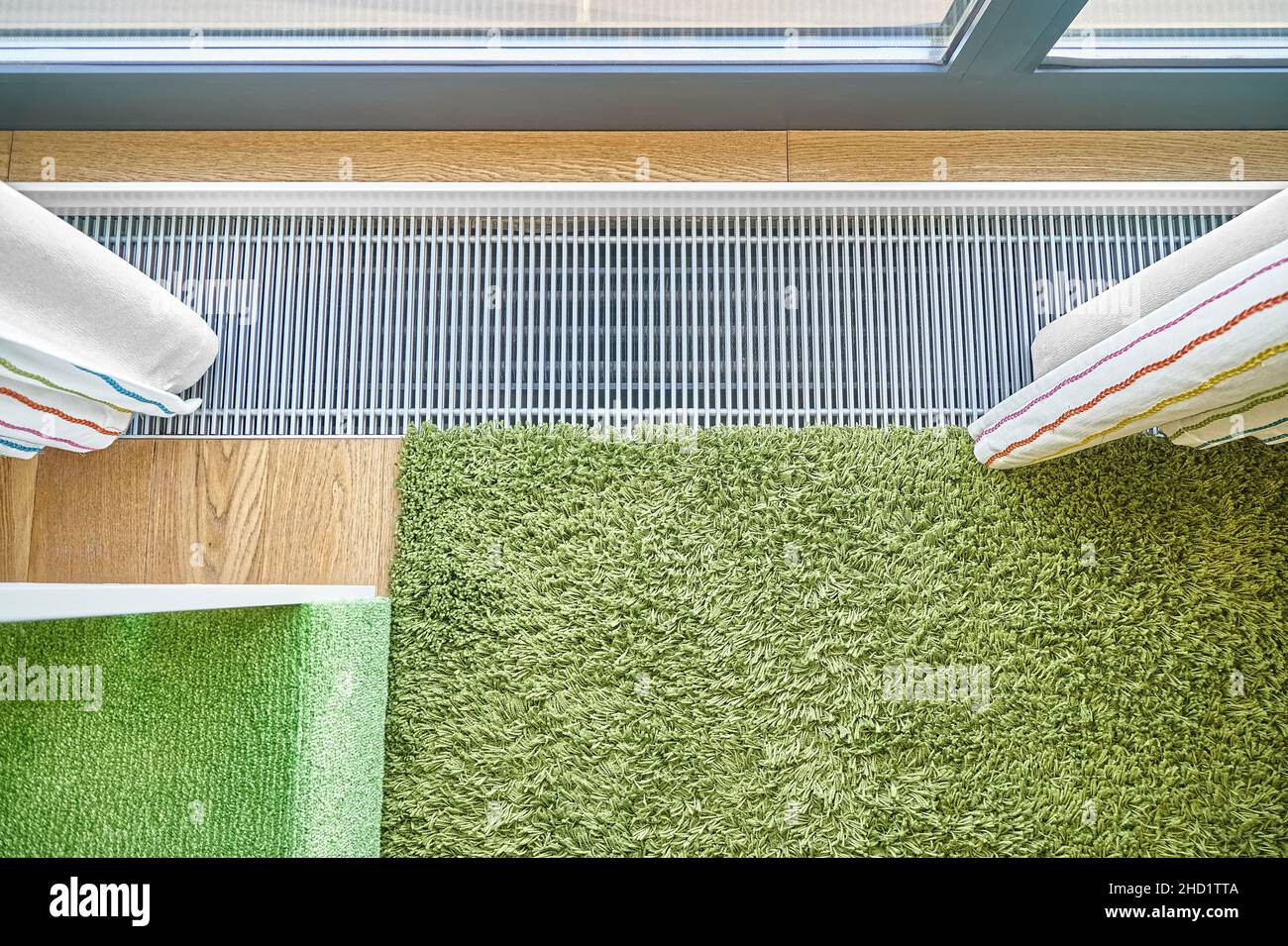 Moderne Wasser warmen Boden Konvektor in der Nähe Panoramafenster mit Vorhängen und grünen Teppich in renovierten Wohnung oberen Blick installiert Stockfoto
