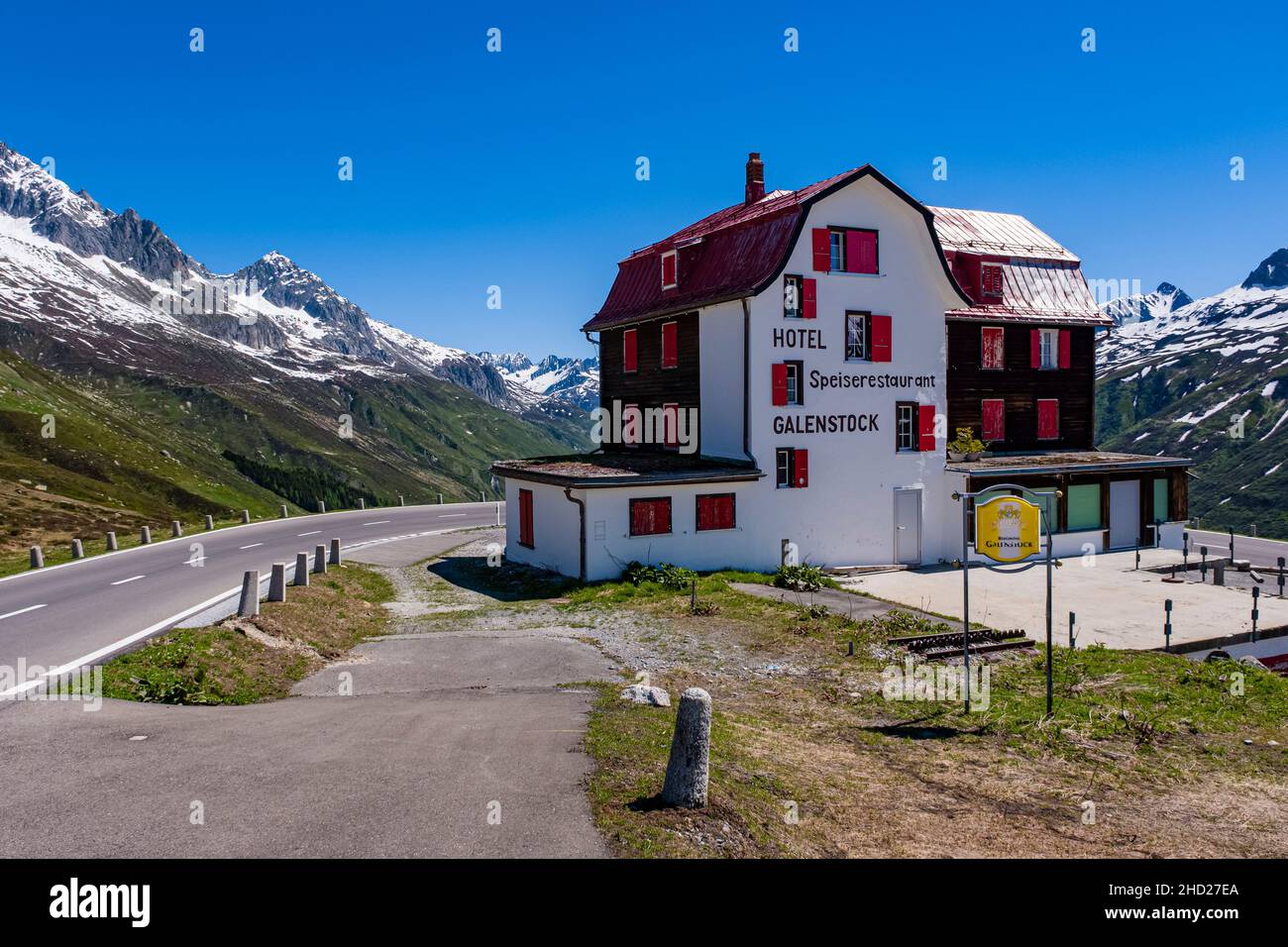 Das Hotel Galenstock liegt an der Furka Pass Straße, schneebedeckte Berge über Andermatt in der Ferne. Stockfoto