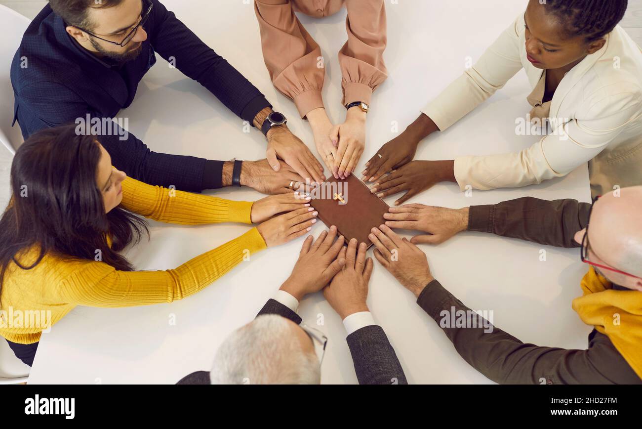 Eine Gruppe von Menschen, die an Christus glauben und die Hand an der Bibel halten und gemeinsam beten Stockfoto