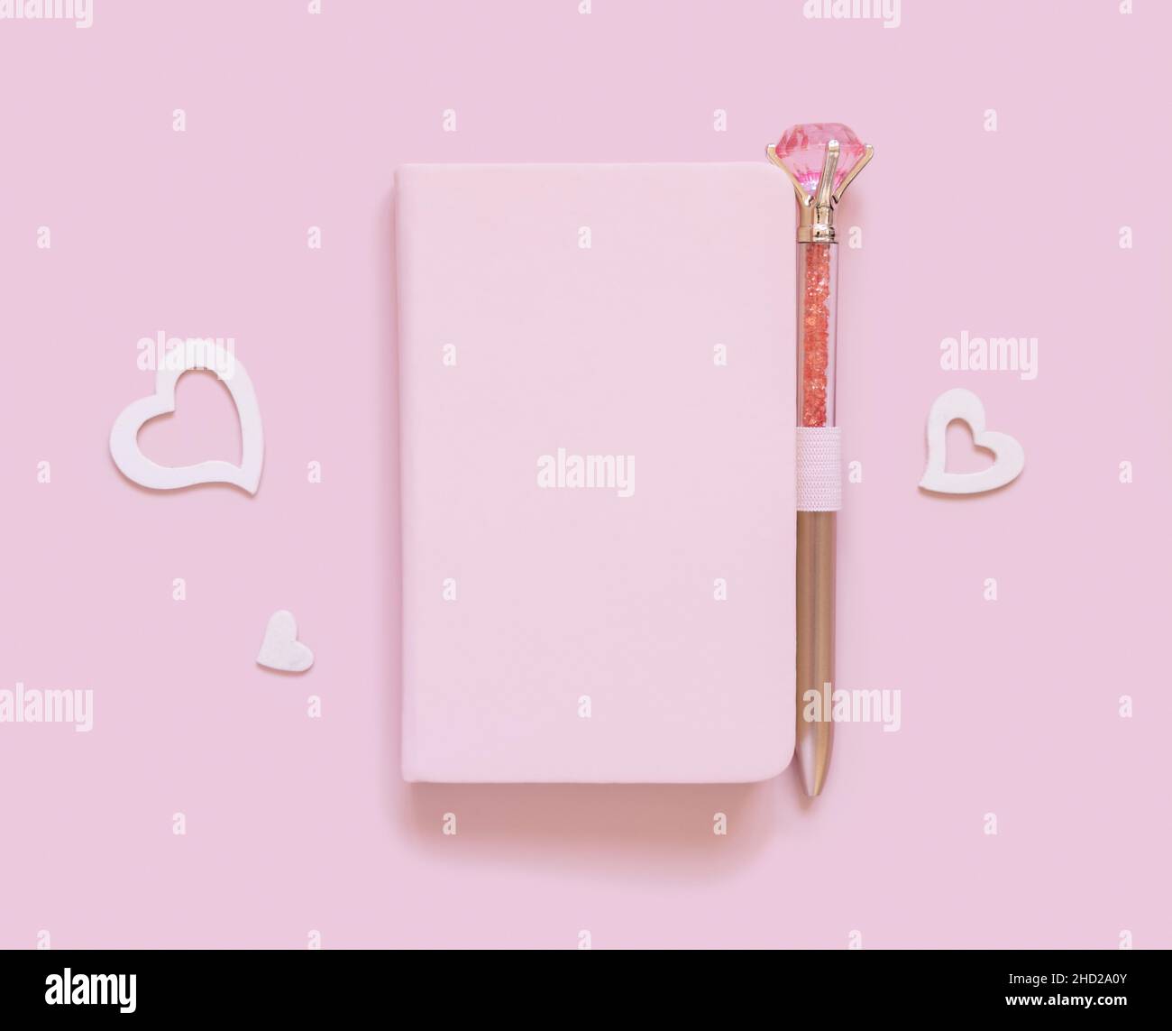 Pinkes Notizbuch, dekorativer Edelsteinschreiber und Herzen auf hellrosa Draufsicht. Minimale Szene mit Textbuch-Mockup. Planner-Cover mit Platztext. Valen Stockfoto