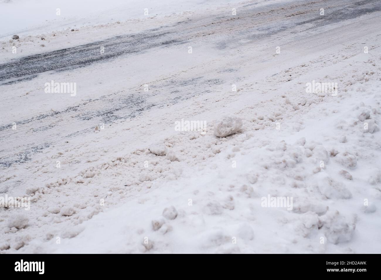 Rutschige, schneebedeckte Stadtstraße im Winter. Schwierige Wetterbedingungen. Straße und Gehweg unter Schneepfählen. Gefährlicher Verkehr. Stockfoto