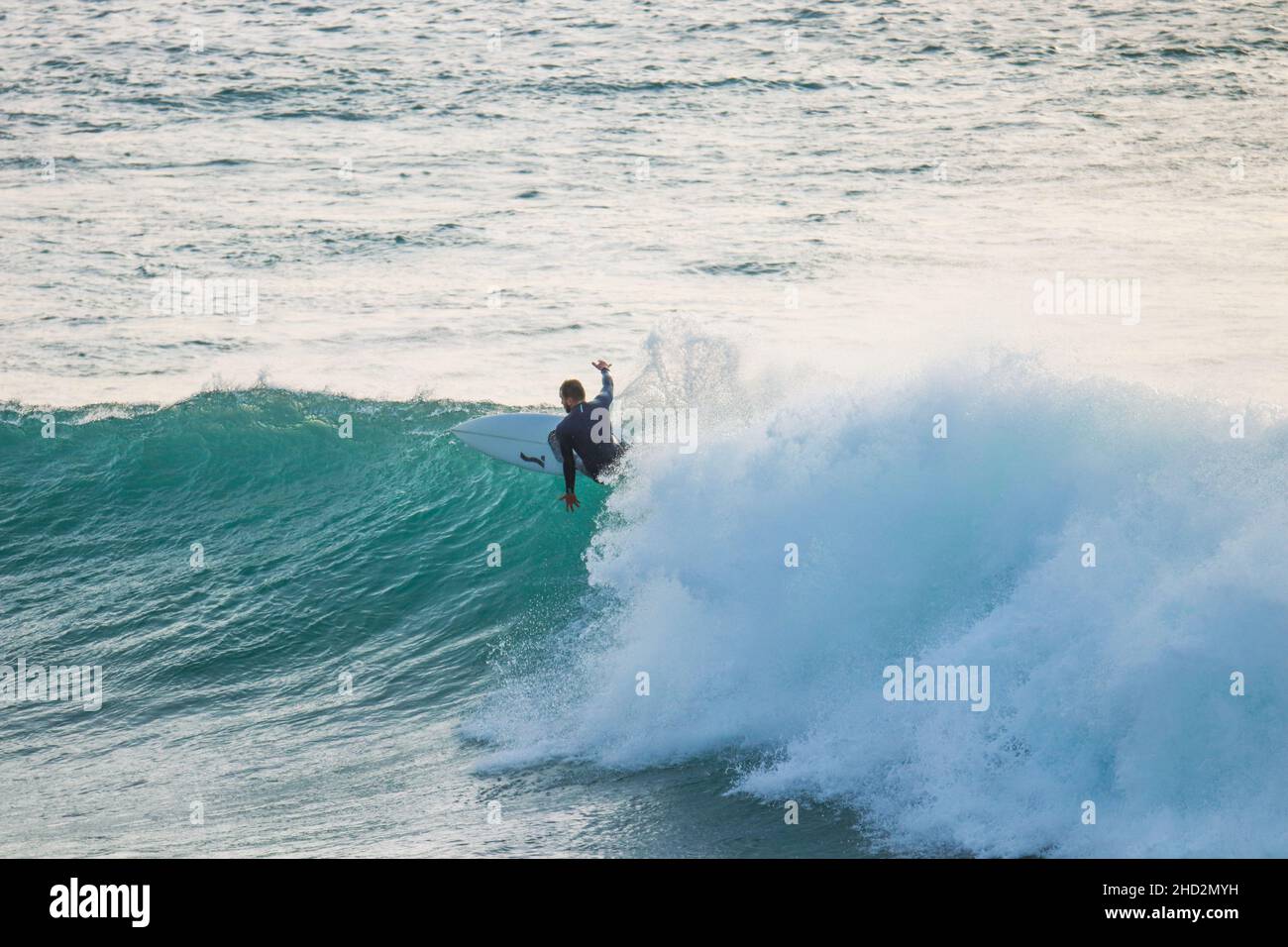 Surfer auf einer blauen Welle an sonnigen Tagen in Ericeira in Portugal. Stockfoto