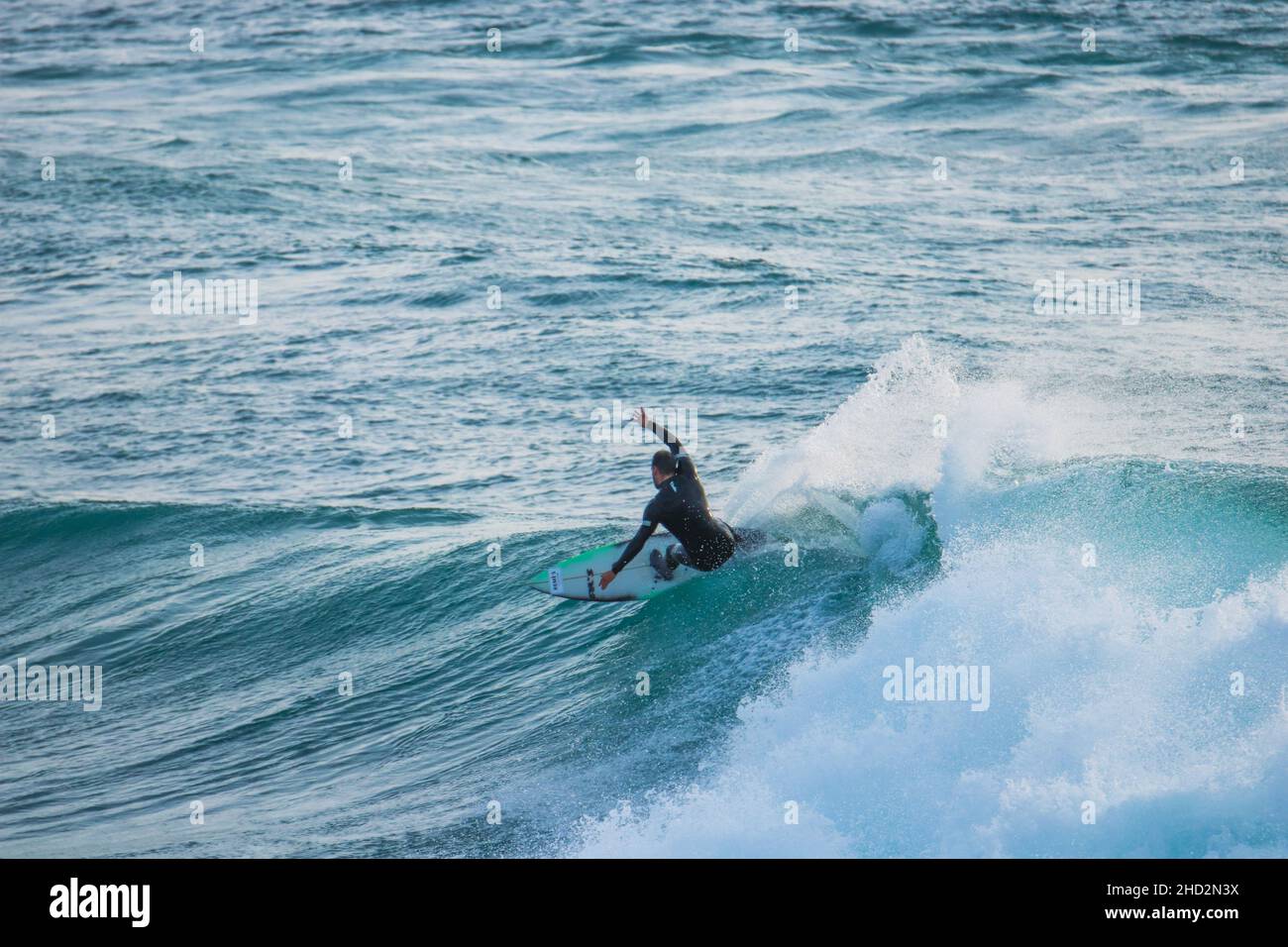 Surfer auf einer blauen Welle an sonnigen Tagen in Ericeira in Portugal. Stockfoto