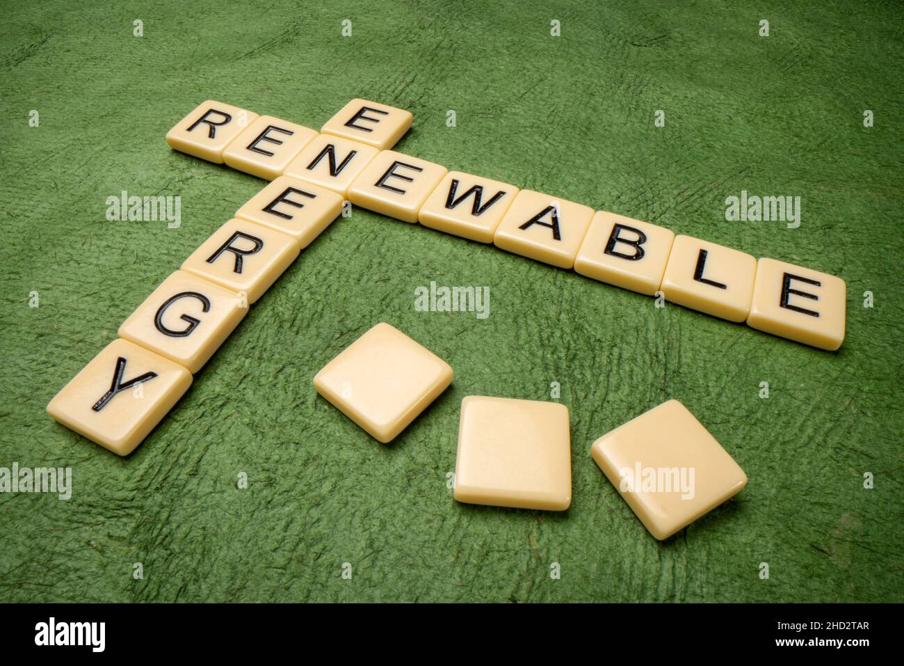 Kreuzworträtsel für erneuerbare Energien in Elfenbein-Buchstabenkacheln gegen grünes strukturiertes handgefertigtes Papier Stockfoto