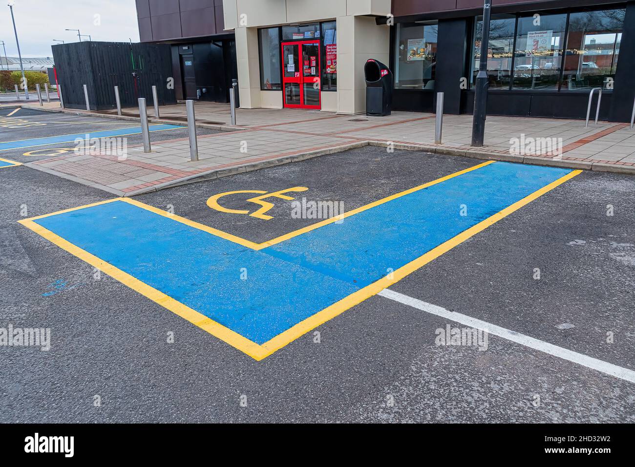 Internationales Behindertensymbol in leuchtendem Gelb auf einem Parkplatz in einem Einkaufszentrum. Stockfoto