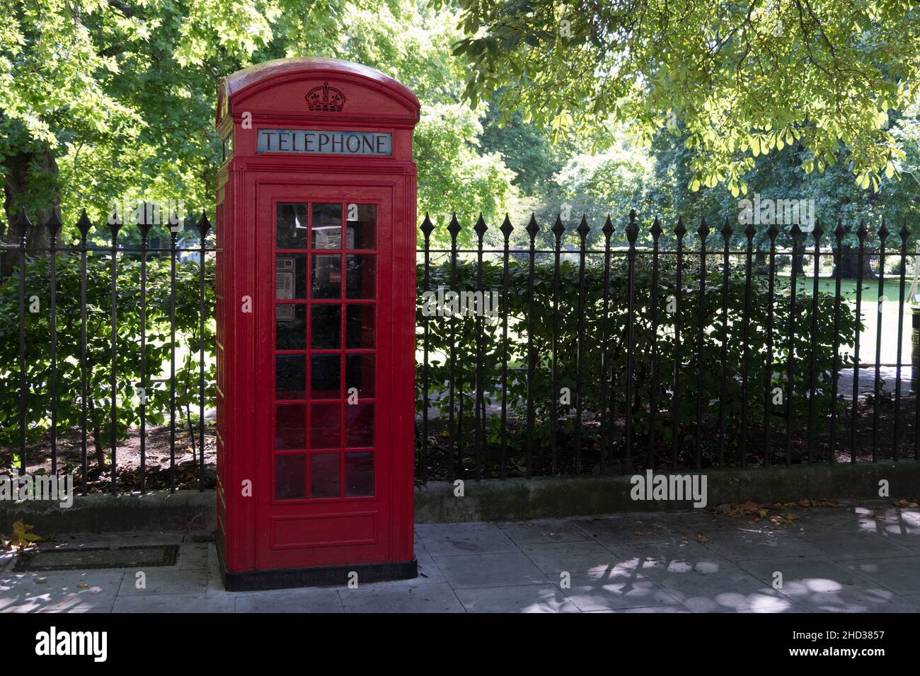 Alte Telefonzelle neben einem eingezäunten Garten in London, England, Großbritannien Stockfoto